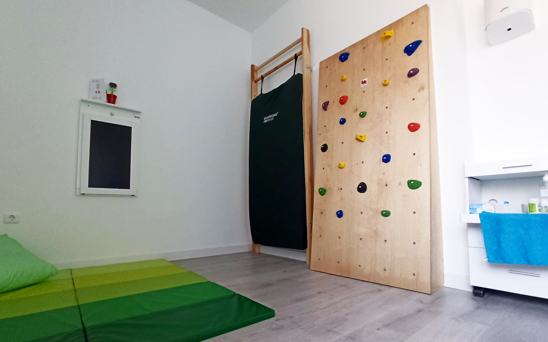 Sala con rocódromo y colchonetas verdes