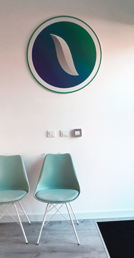 Sala de espera con el logotipo de Neuroglía y dos sillas verde agua